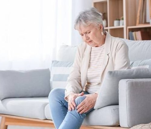Senior woman suffering from pain in knee at home